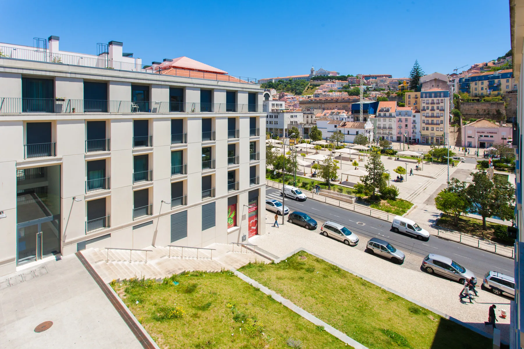 A modern building overlooks a landscaped plaza and a city street.