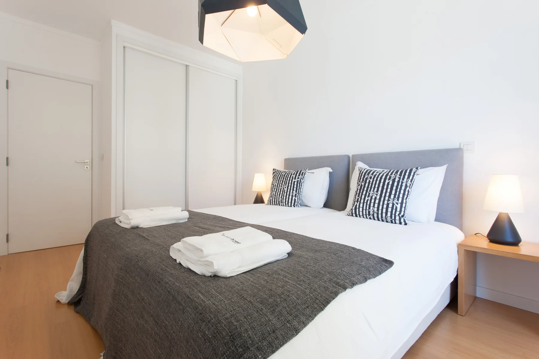 A bright bedroom with a neatly made bed and bedside lamps.