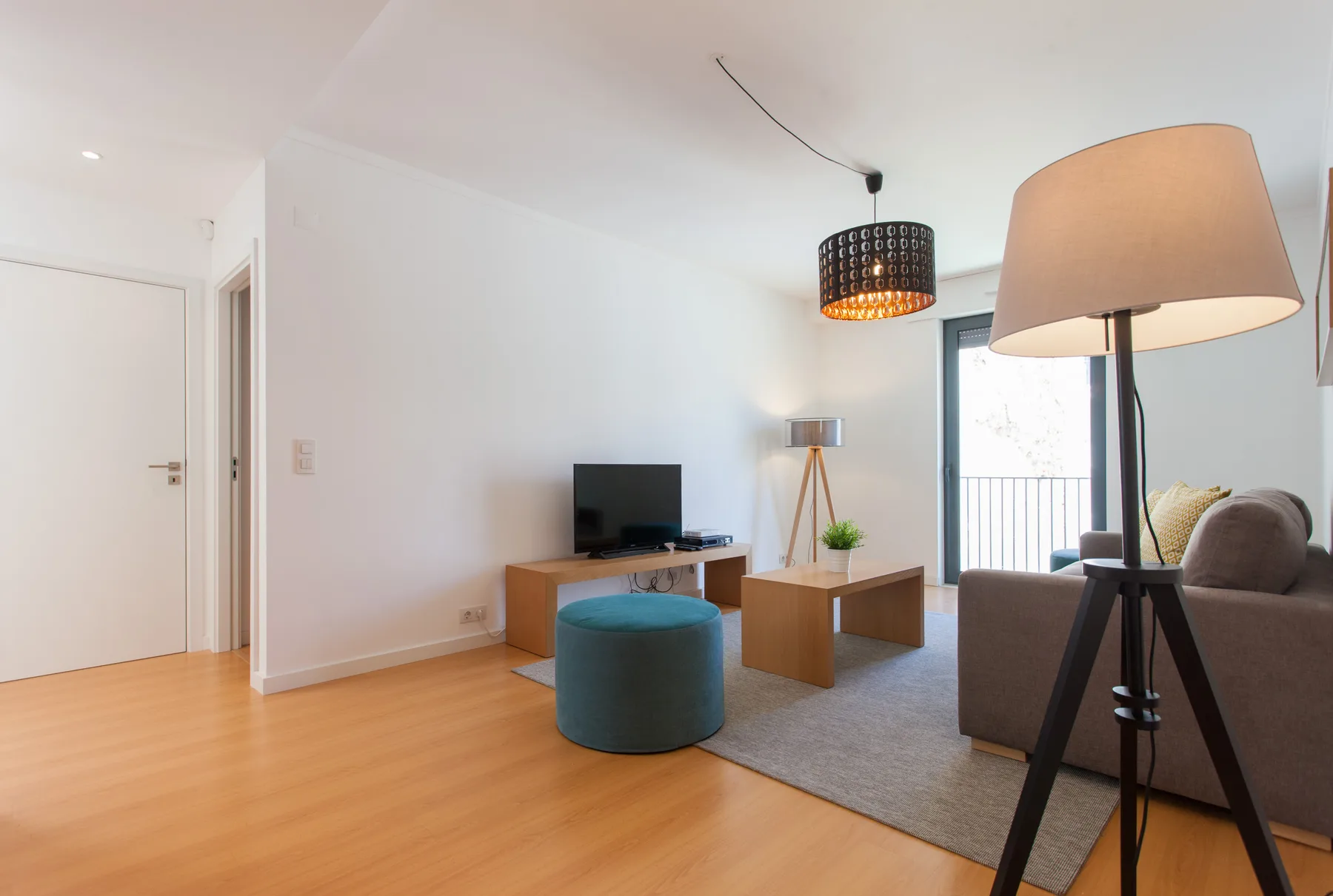 A bright living room with a television, seating, and a large floor lamp.
