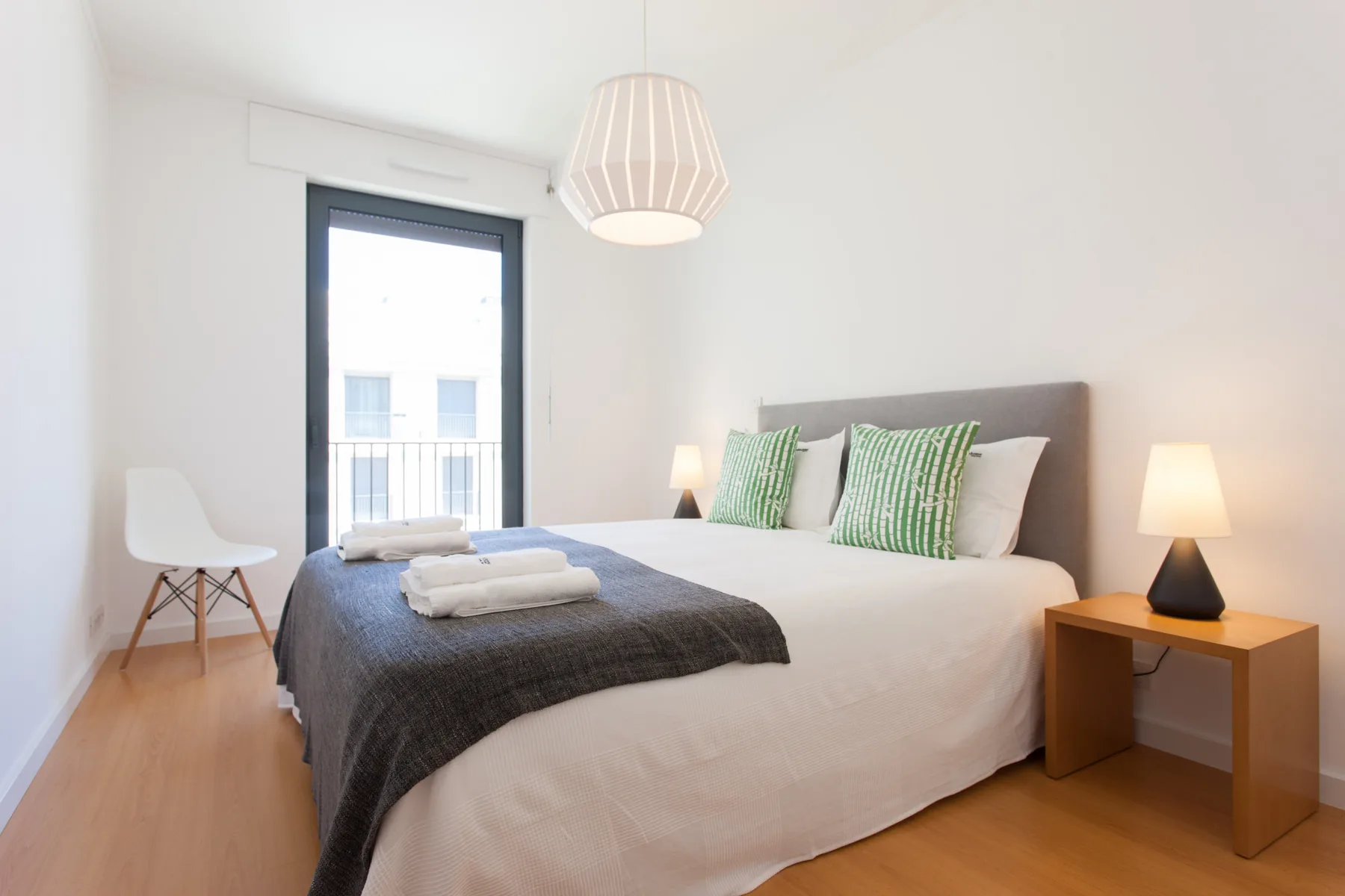 A bright bedroom with a large bed and green accent pillows.