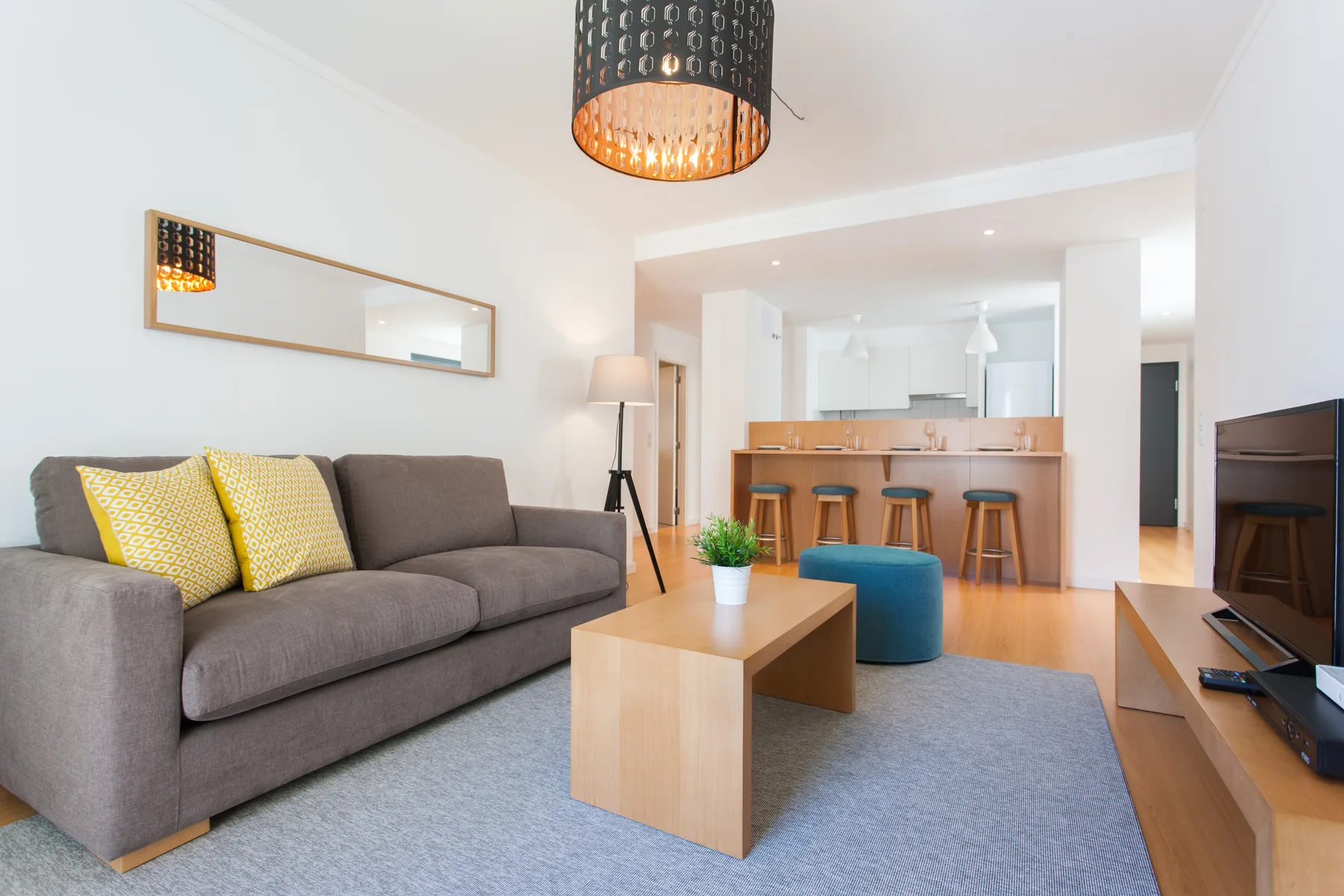 A bright living room with seating, a coffee table, and an open kitchen.