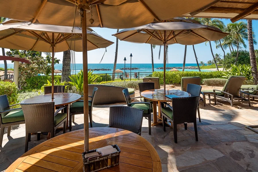 Un patio al aire libre con asientos y sombrillas da al mar.