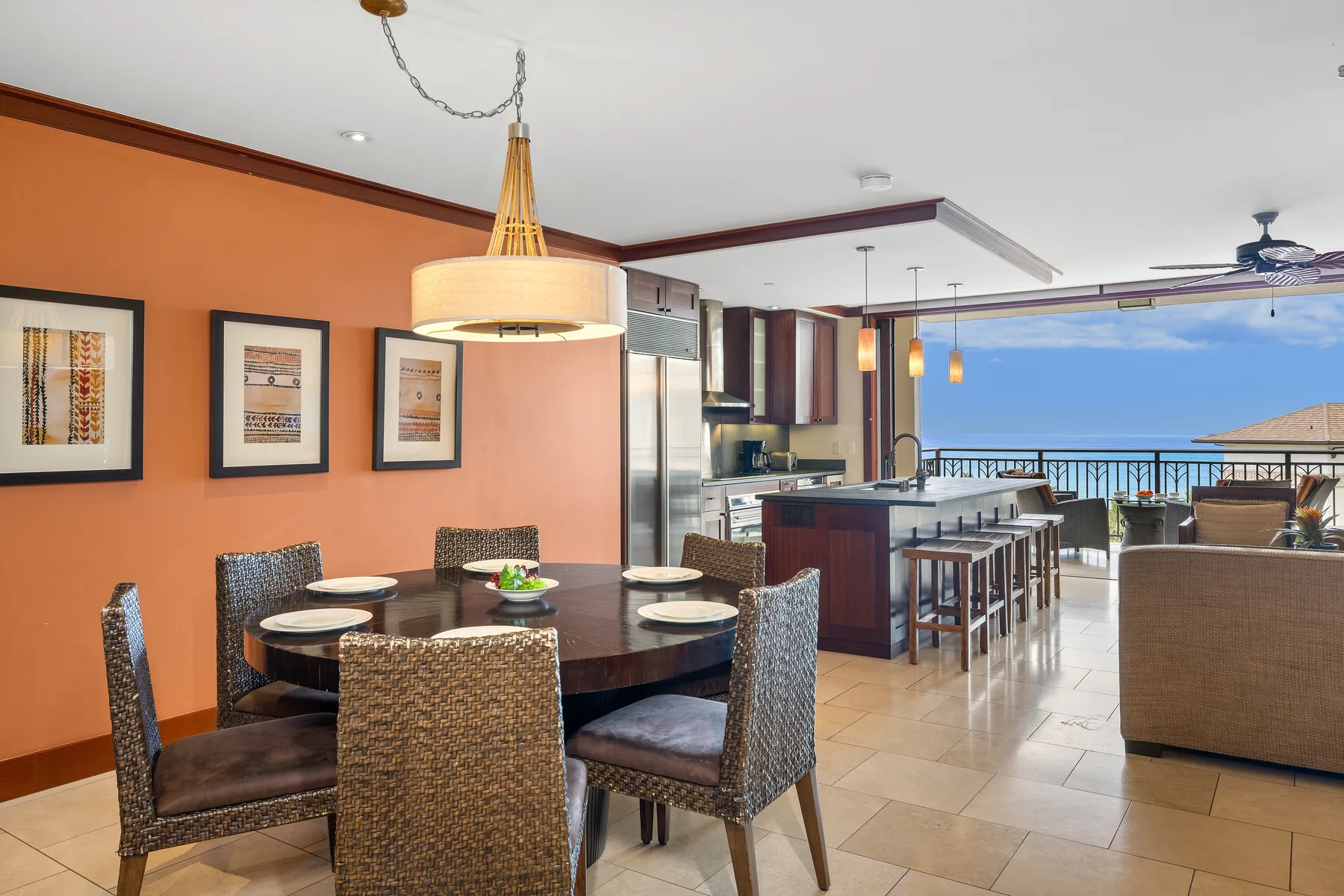 Comedor con mesa y sillas junto a una barra de cocina y un balcón abierto.