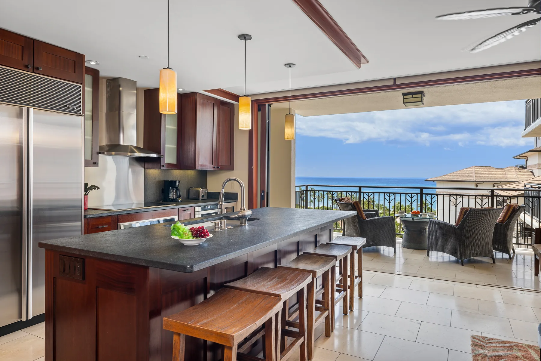 Una cocina con una isla larga se abre a un balcón con vista al mar.