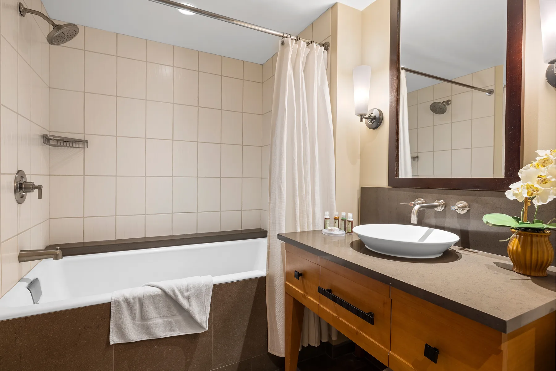 Un baño con bañera, ducha y lavabo bajo un espejo grande.
