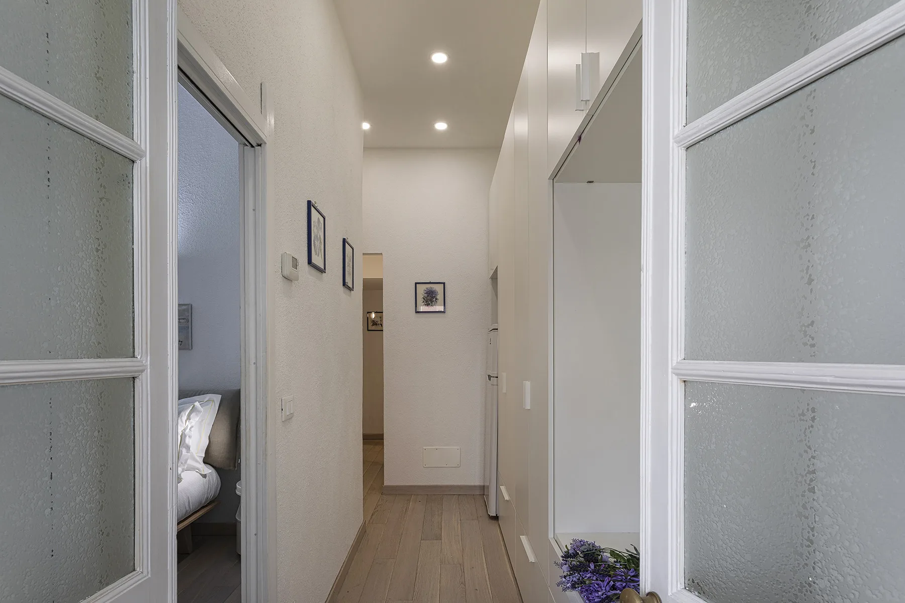 A bright hallway with framed pictures and a wood-toned floor.