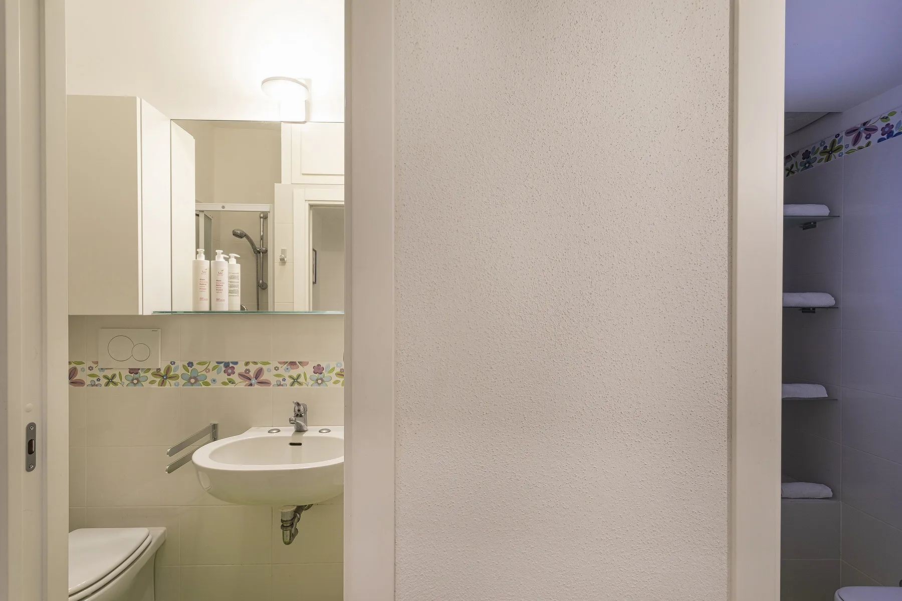 A bathroom vanity and mirror are visible beside a recessed shower area.