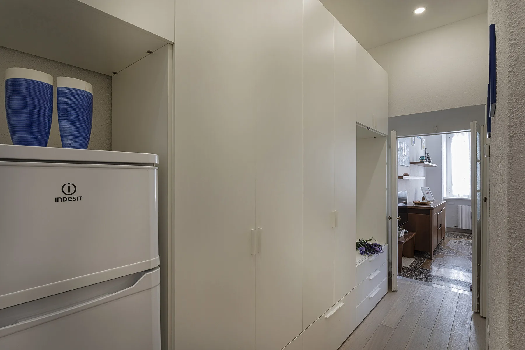 A hallway with built-in cabinets leads to a bathroom.