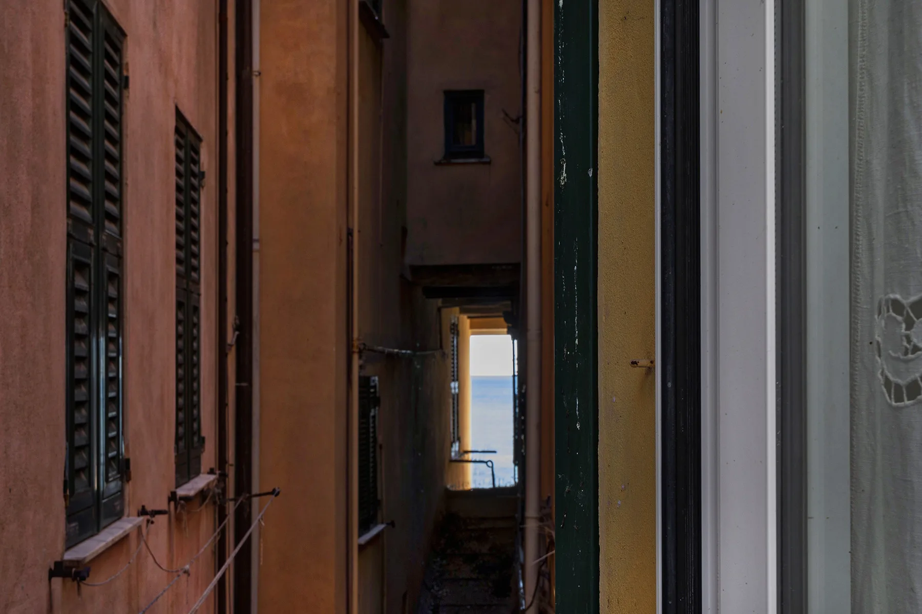 A narrow passage between buildings opens onto a view of the sea.