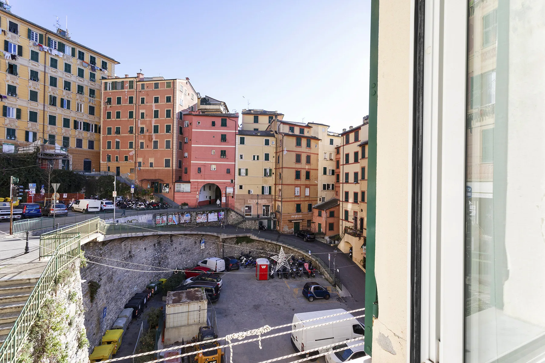 A view from a window overlooks colorful city buildings and a small paved courtyard.