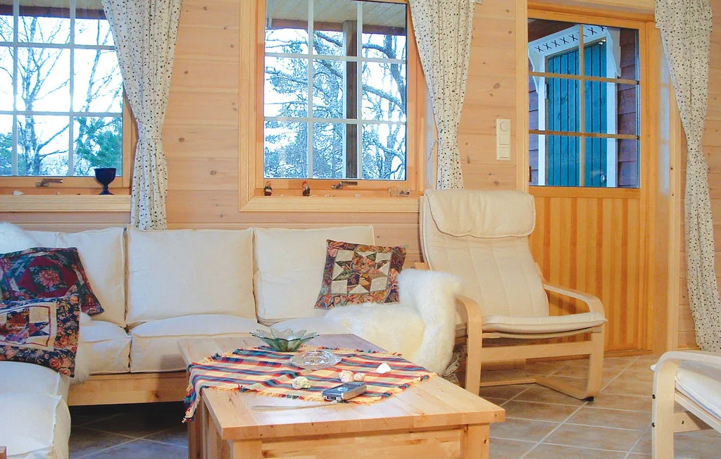 A wood-paneled living room with seating, a low table, and curtained windows.
