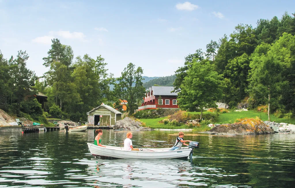 People ride in a small boat on a calm, tree-lined inlet.