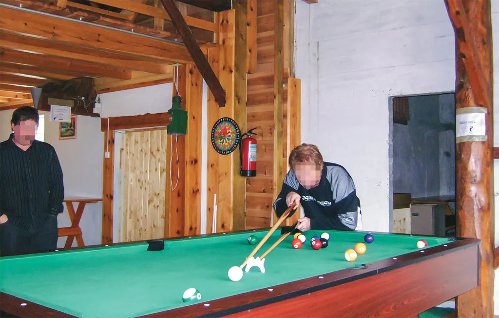 A recreation room with a green pool table and players lining up shots.