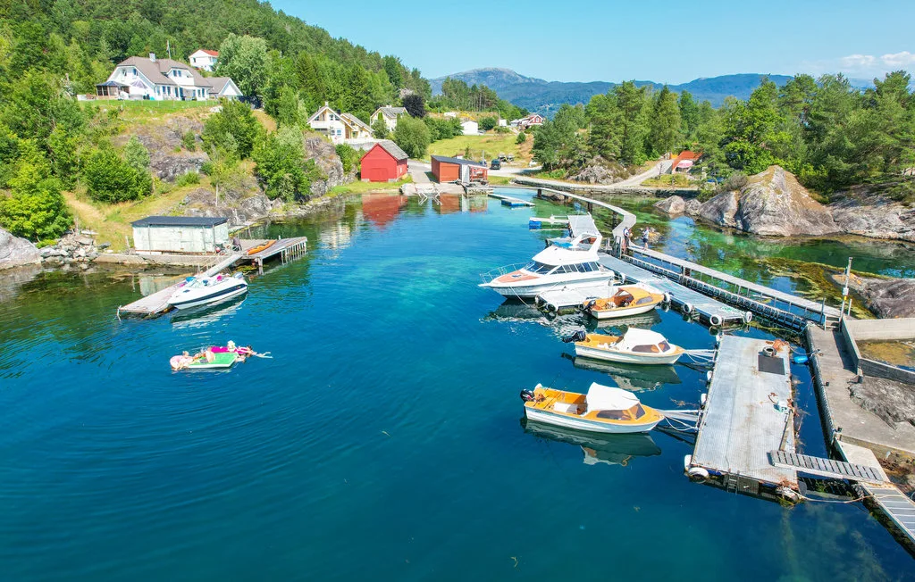A small marina with boats moored along floating docks in a wooded coastal inlet.