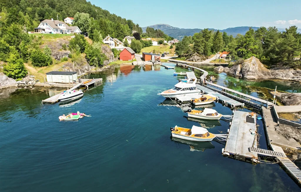 A waterfront marina with boats moored along docks beside a wooded shoreline.