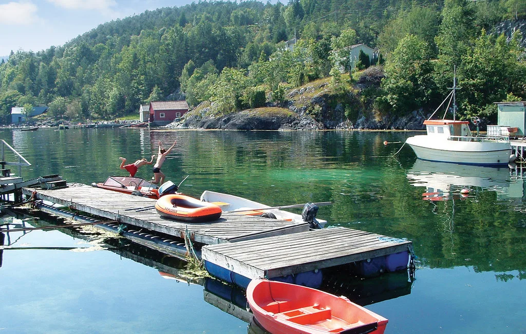 A floating dock with small boats sits on a calm, wooded waterfront.
