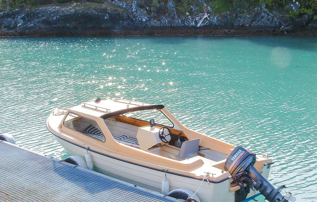 A small motorboat floats beside a dock on turquoise water.