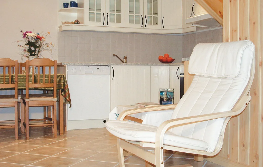 A kitchen and dining area with wooden seating and a cushioned armchair.
