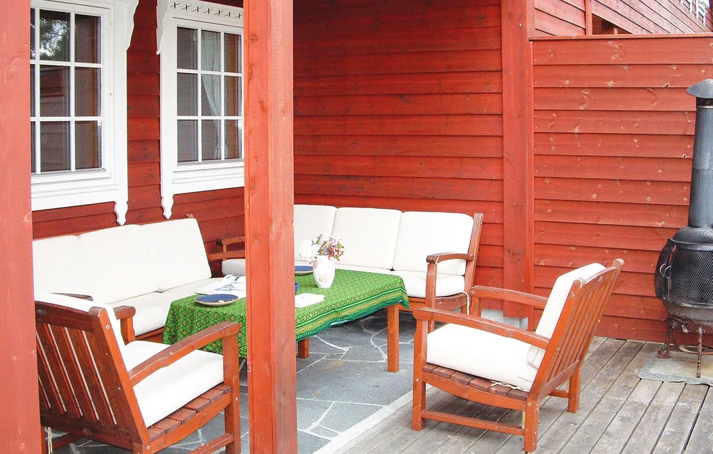 A covered outdoor seating area with wooden furniture and a green tablecloth.