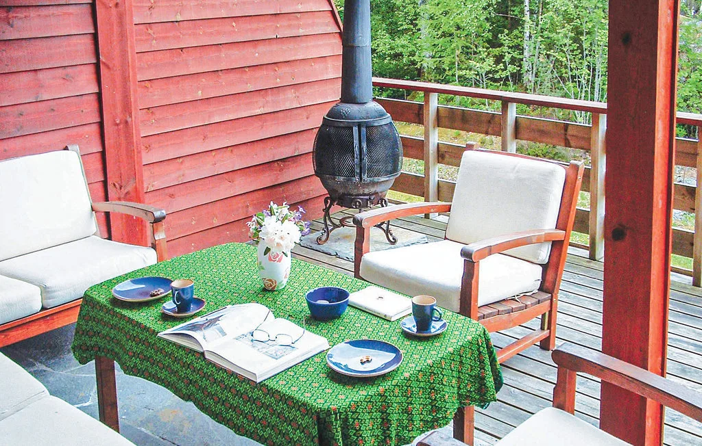 A covered deck seating area with a green tablecloth and outdoor chairs.