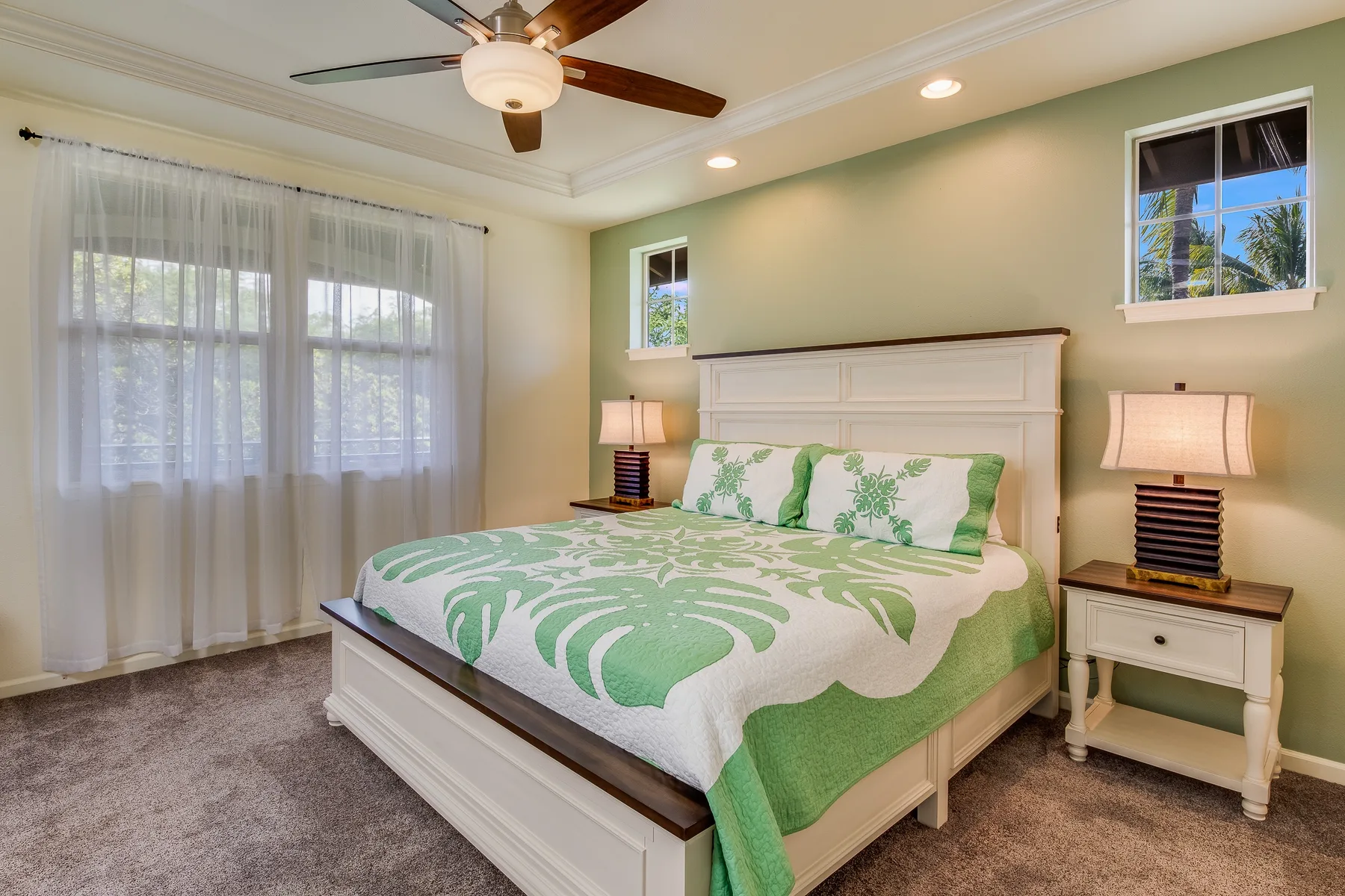 Un dormitorio con una cama vestida con ropa de cama verde y blanca y lámparas a los lados.