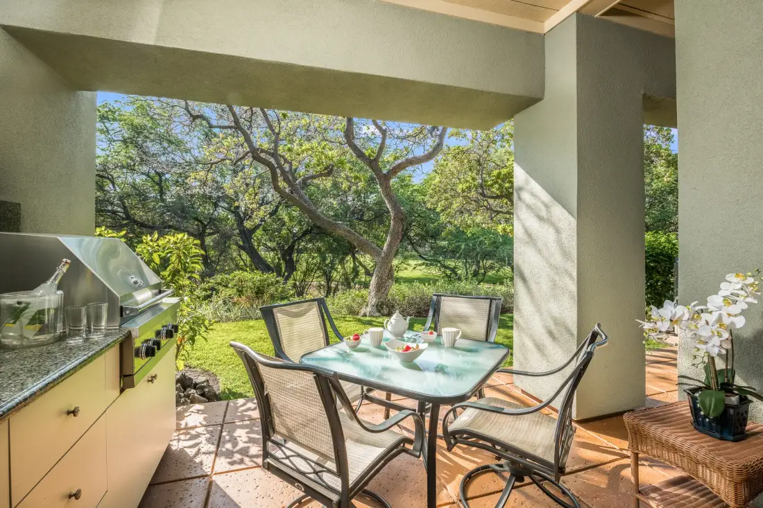 An outdoor dining area with a glass table and garden views.