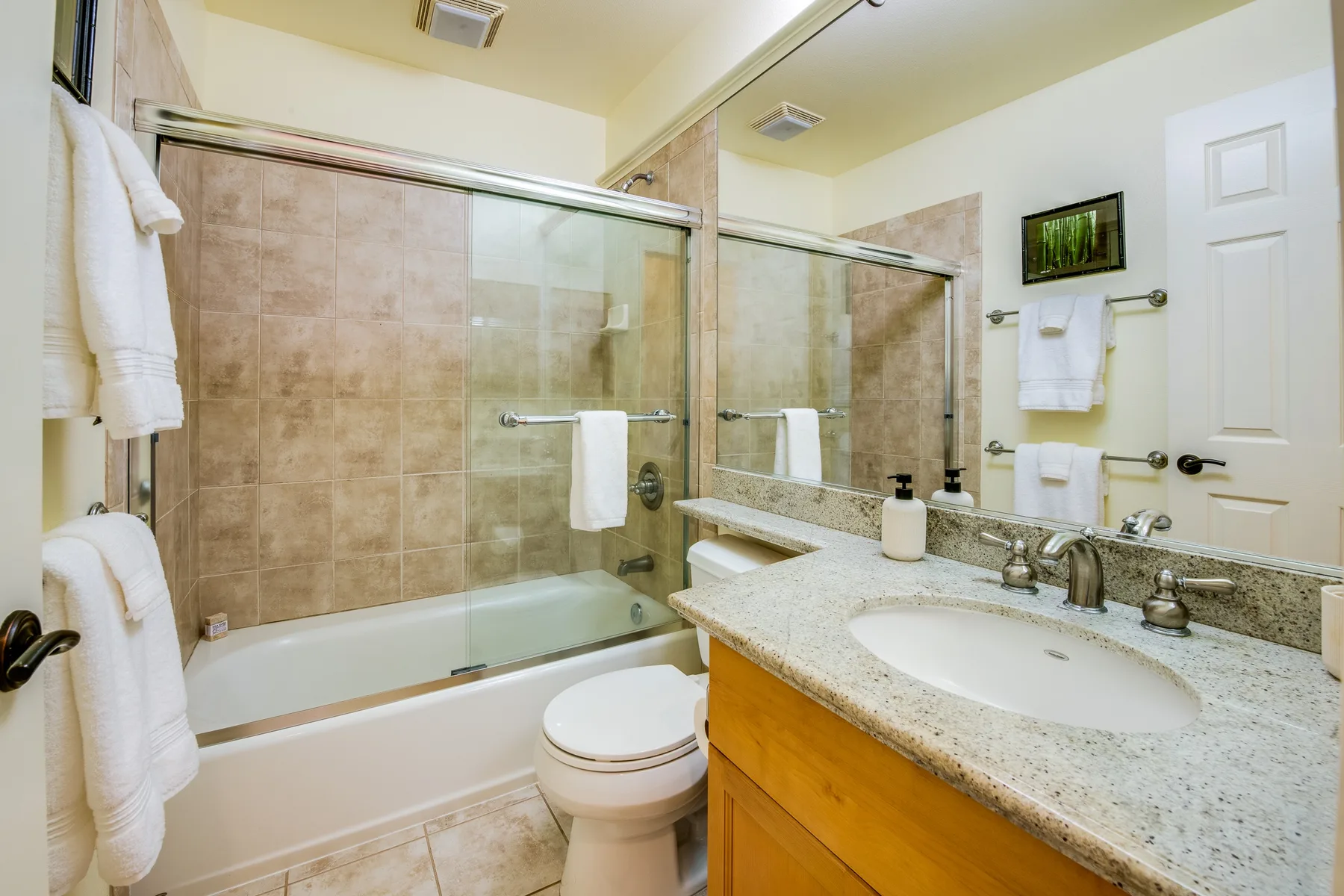 Un baño con bañera, mampara de vidrio y lavabo.