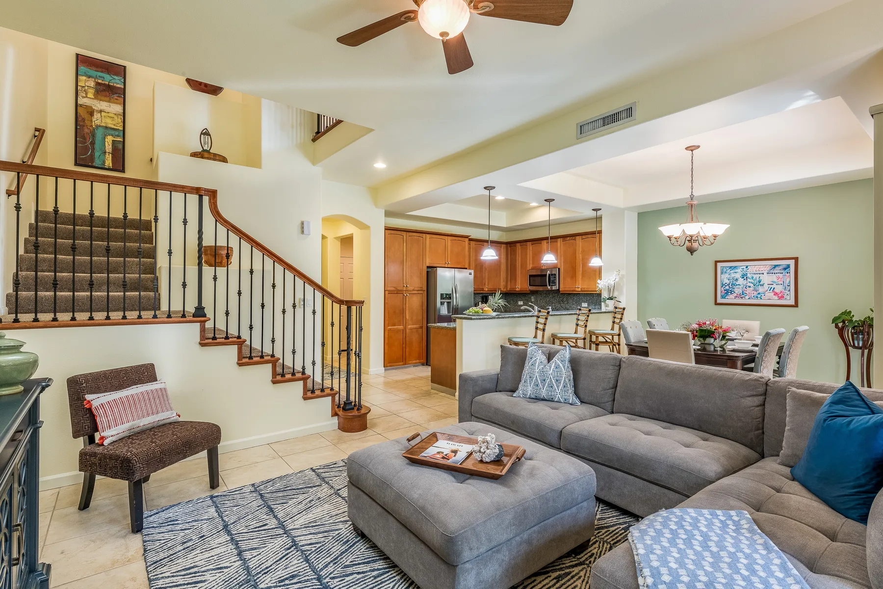 Open-plan living room with a gray seating area beside the kitchen and staircase.