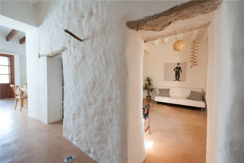 A bright interior hallway opens into a sitting area with a bench and wall art.