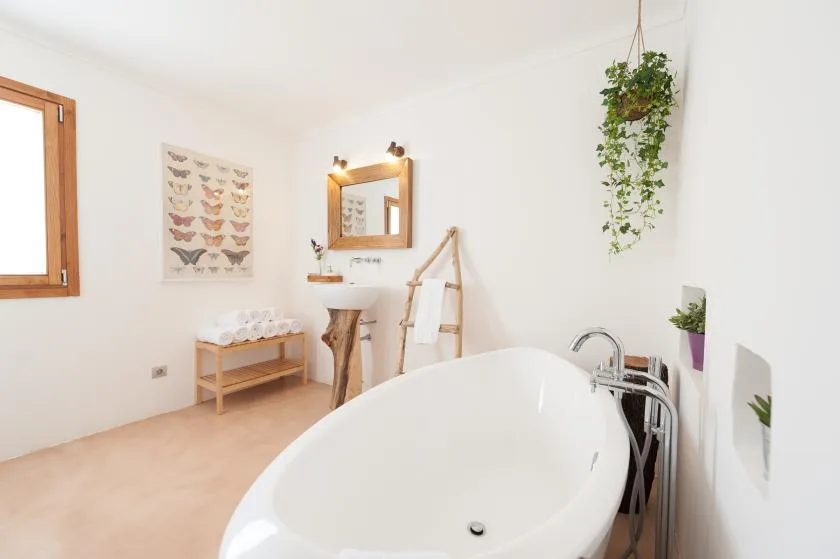 A bright bathroom with a freestanding bathtub and a small sink.