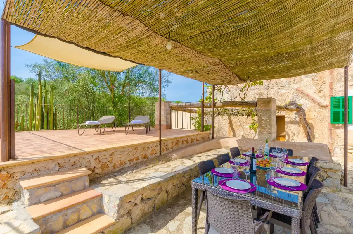 A shaded outdoor dining area with a set table beside a raised wooden deck.