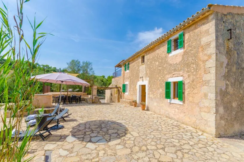 A stone-paved courtyard beside a building, with outdoor seating under a patio umbrella.