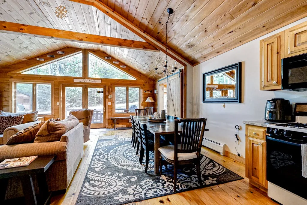 A wood-paneled living and dining area with large windows and a dining table.