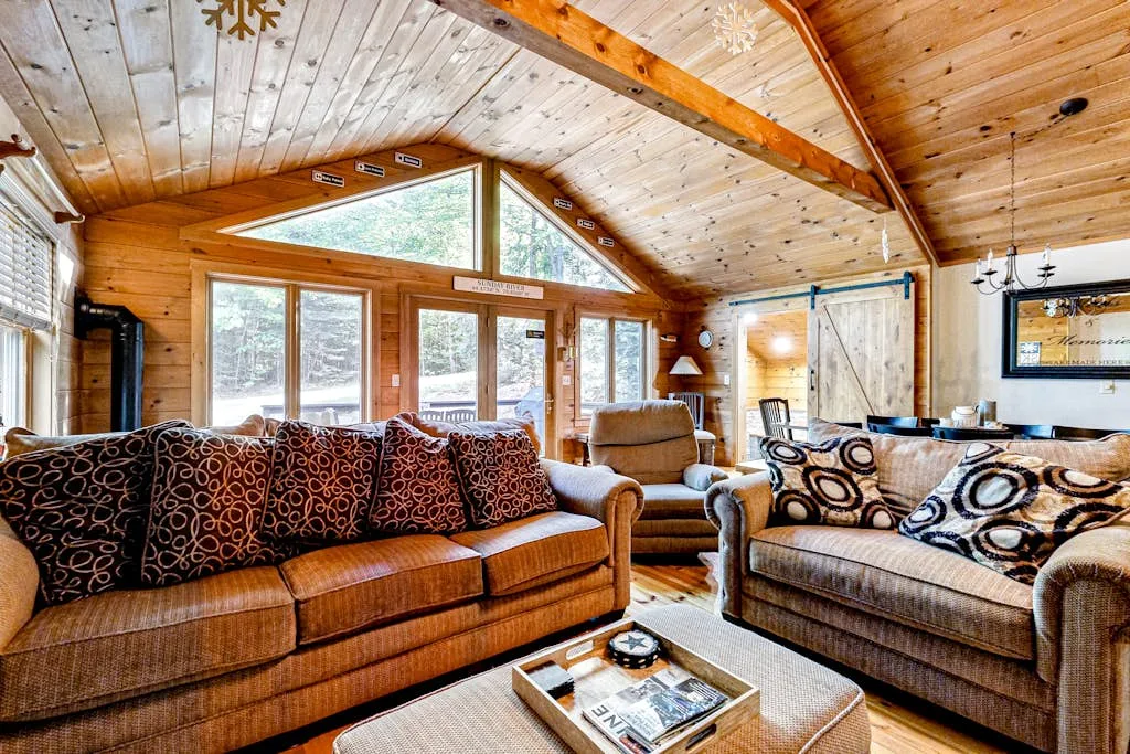 A wood-paneled living room with seating beside large windows.
