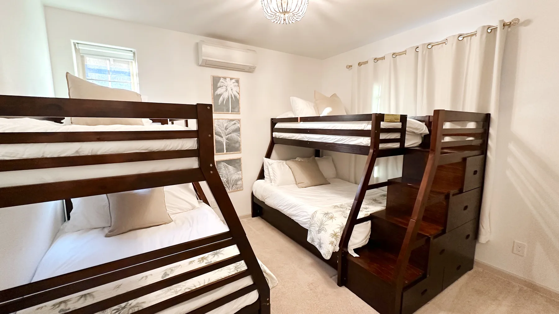Un dormitorio con dos literas de madera oscura, ropa de cama blanca y cortinas.