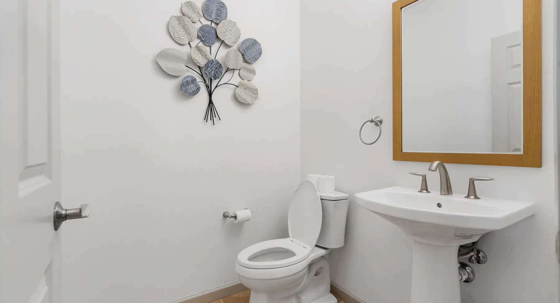 Un baño con inodoro, lavabo de pedestal y espejo de pared.