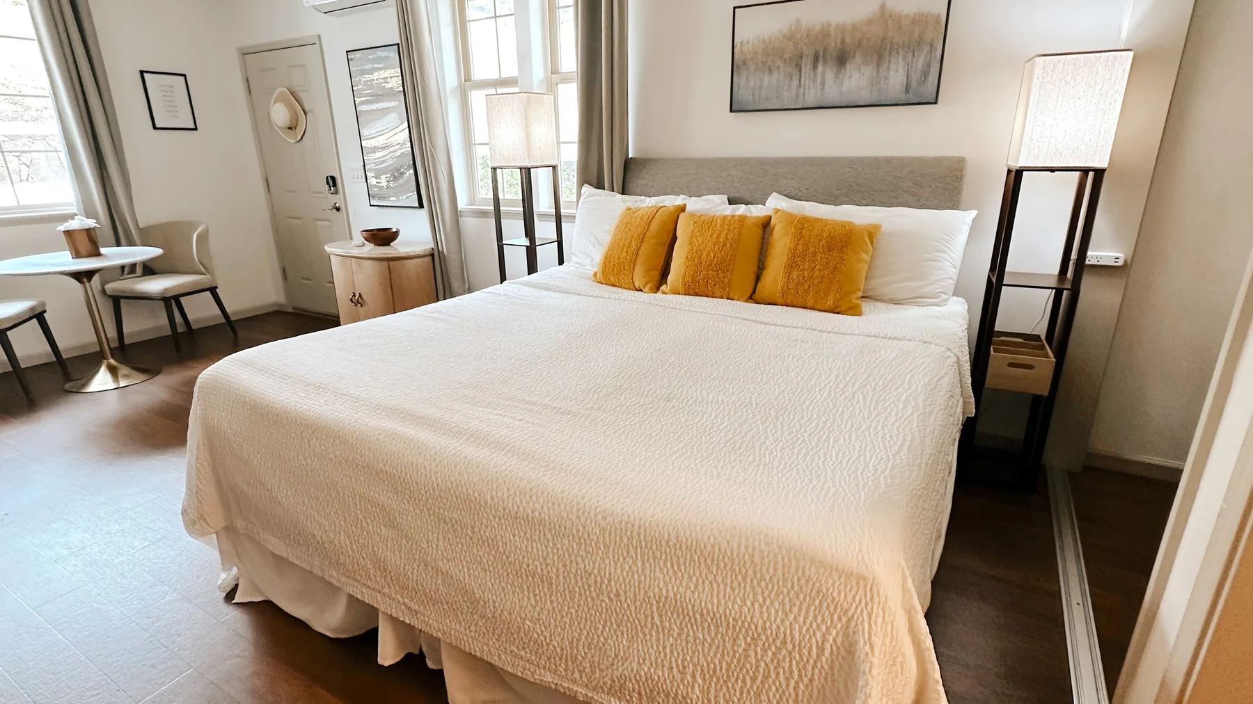 Un dormitorio con una cama tendida y cojines decorativos color mostaza.