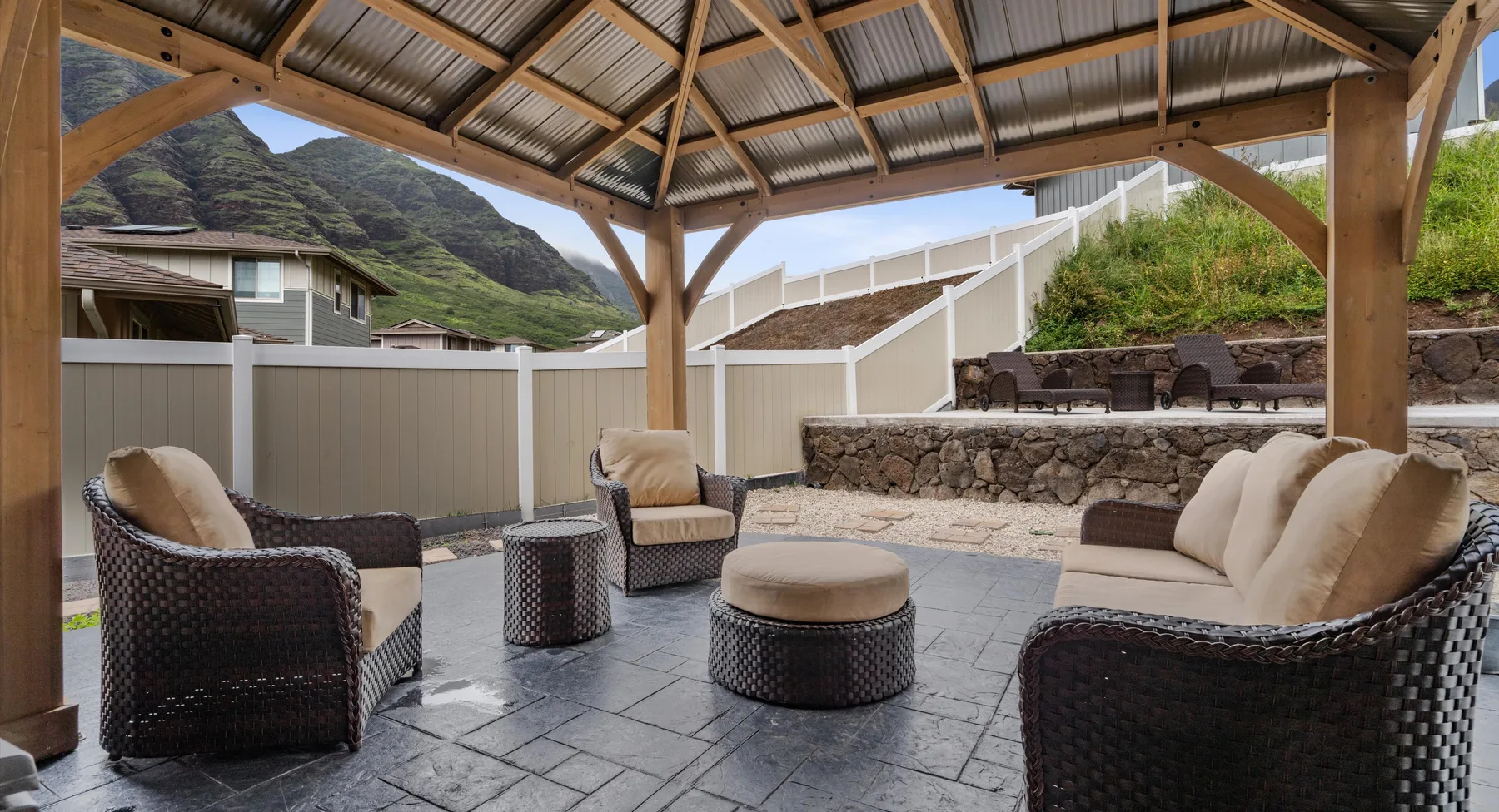 Una zona exterior cubierta con muebles de mimbre acolchados y suelo de piedra.