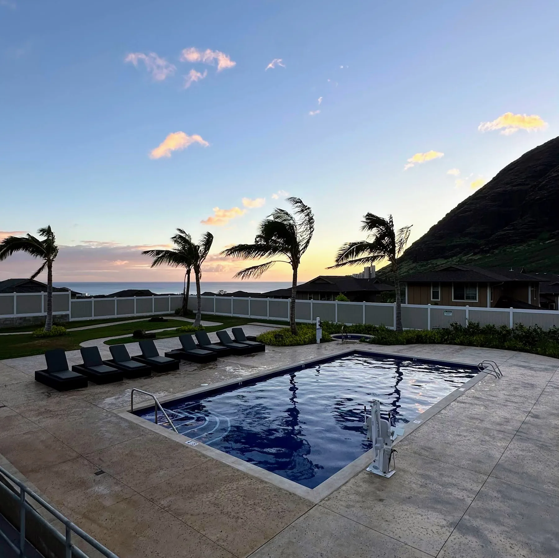 Una piscina al aire libre y asientos miran al océano al atardecer.