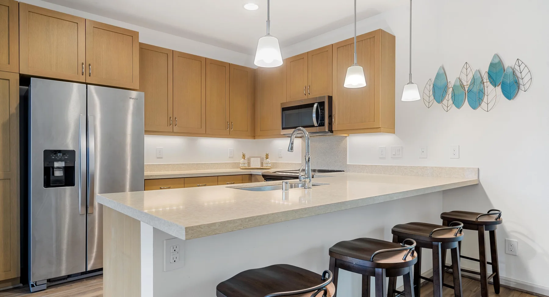 Una cocina luminosa con gabinetes de madera, electrodomésticos de acero inoxidable y una isla amplia.