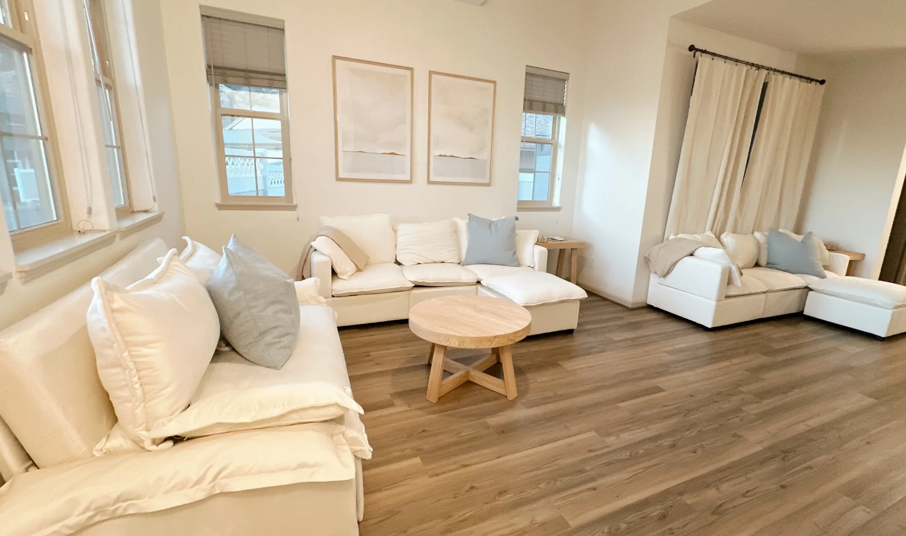 Una sala luminosa con asientos claros y una mesa de centro redonda de madera.