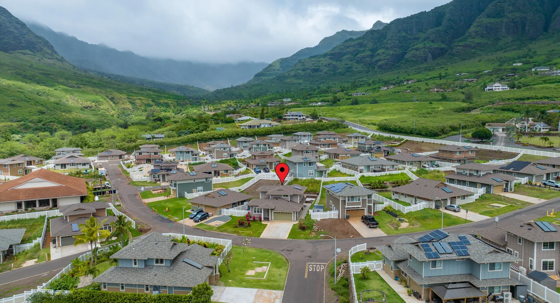 Vista aérea de un barrio residencial rodeado por un valle montañoso verde.