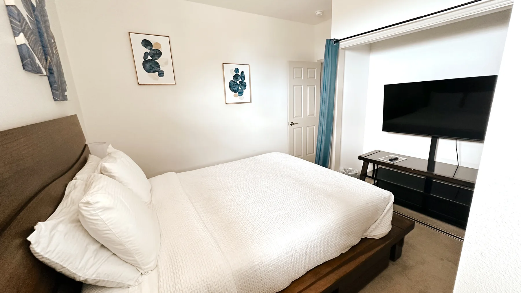 Un dormitorio con una cama bien tendida y un televisor sobre un mueble.