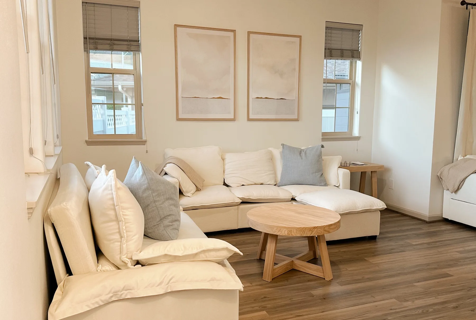 Una sala luminosa con asientos color crema, cuadros enmarcados y una mesa de centro redonda de madera.