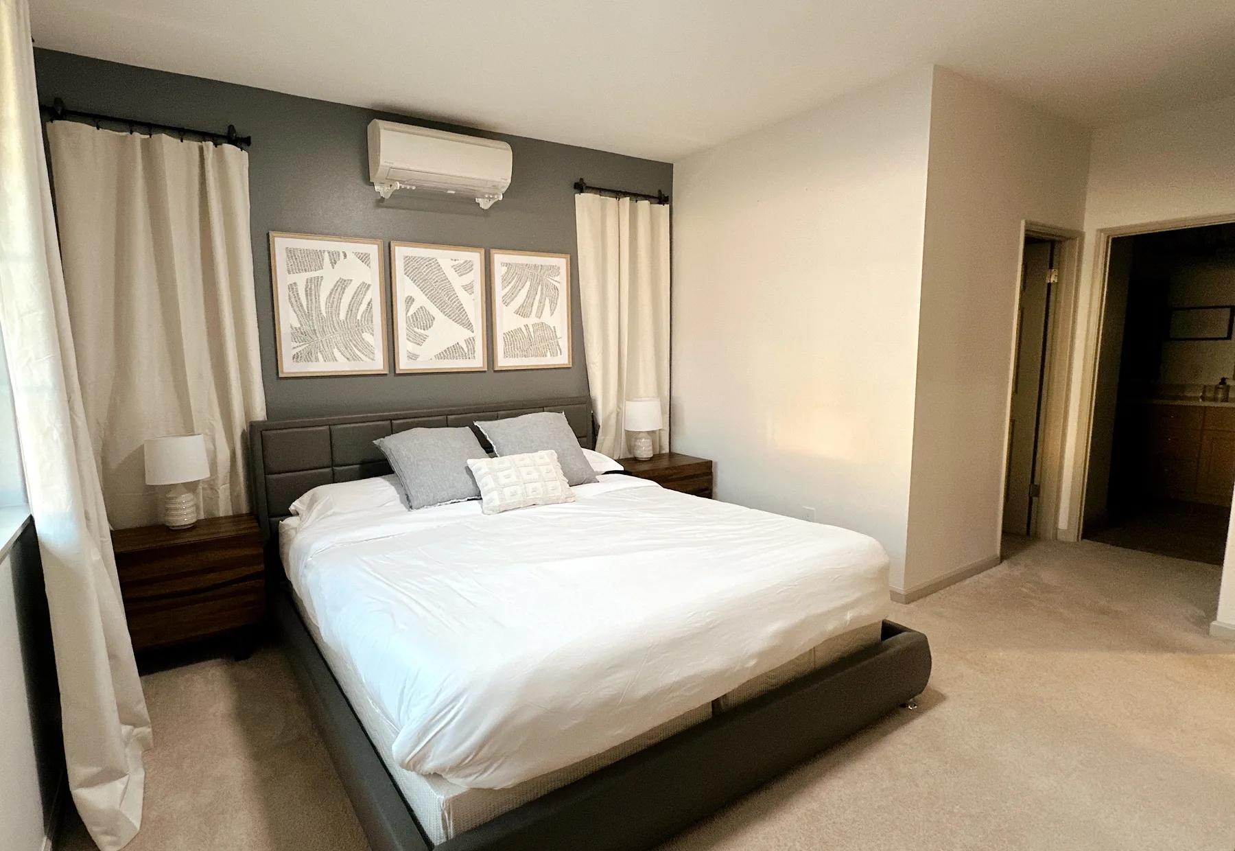 Un dormitorio con una cama bien tendida, mesitas de noche y cuadros enmarcados.