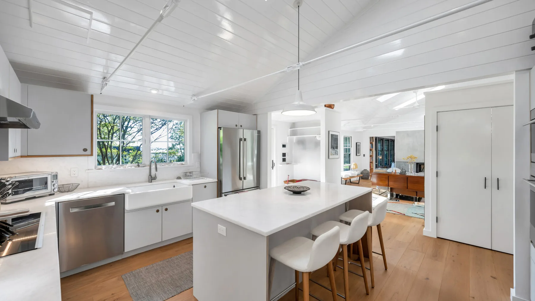 Una cocina luminosa con una isla grande y asientos junto al comedor.