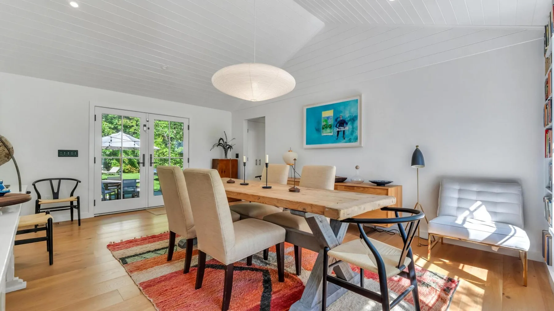 Un comedor luminoso con una mesa larga de madera y sillas sobre una alfombra estampada.