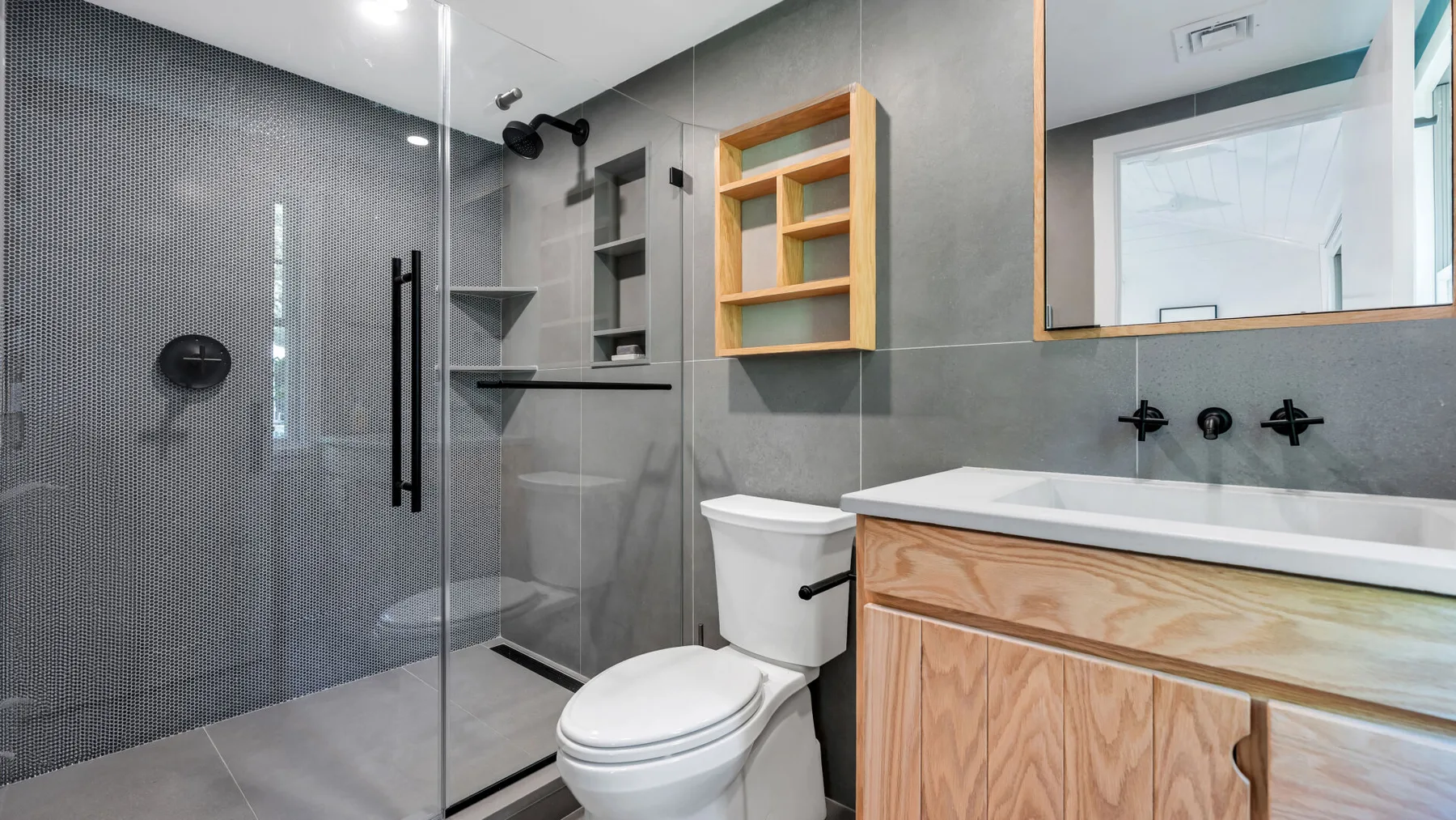 Un baño moderno con ducha de vidrio, inodoro y tocador de madera.
