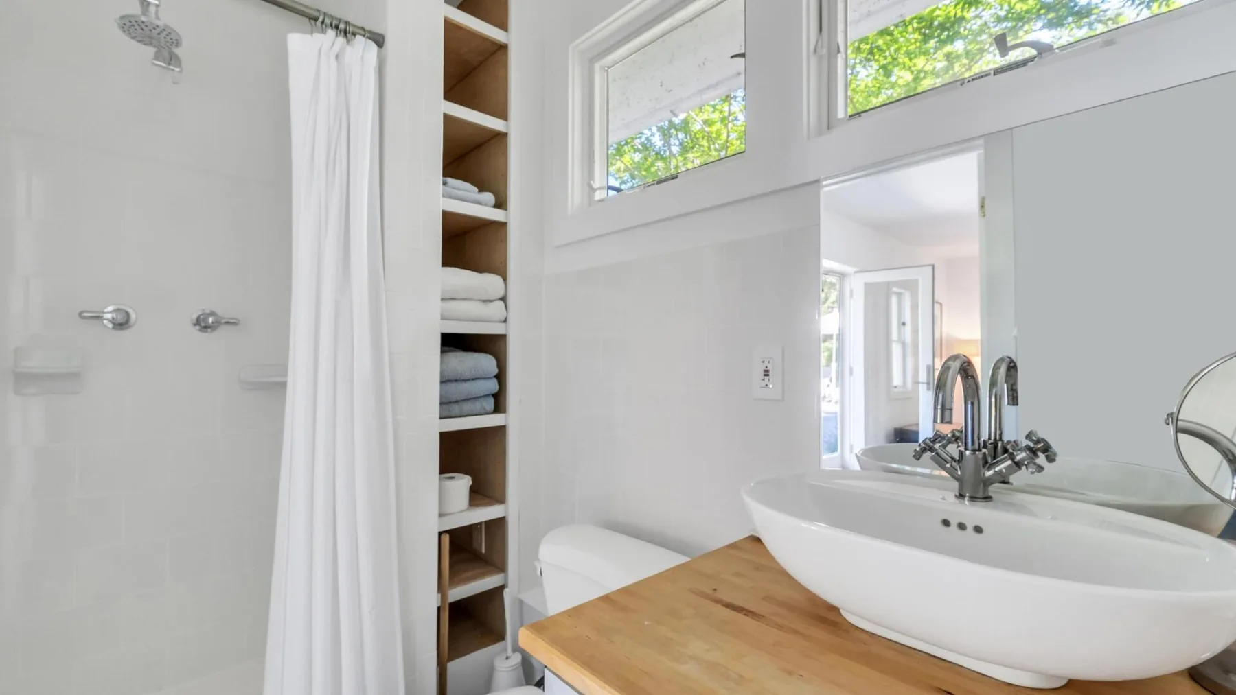 Un baño luminoso con un lavabo blanco y una encimera de madera.