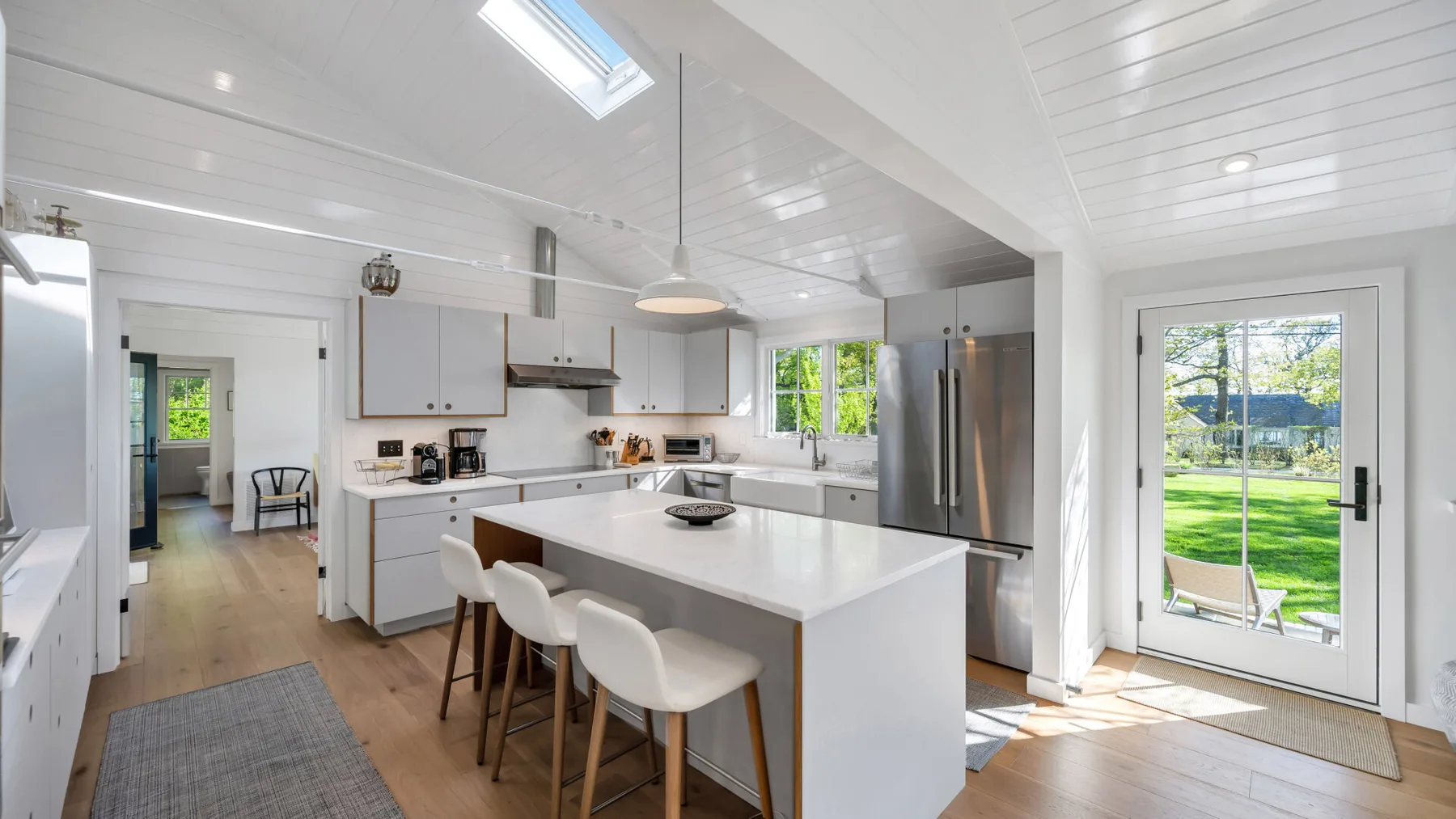 Una cocina luminosa con una isla central y una puerta de vidrio que da al jardín.